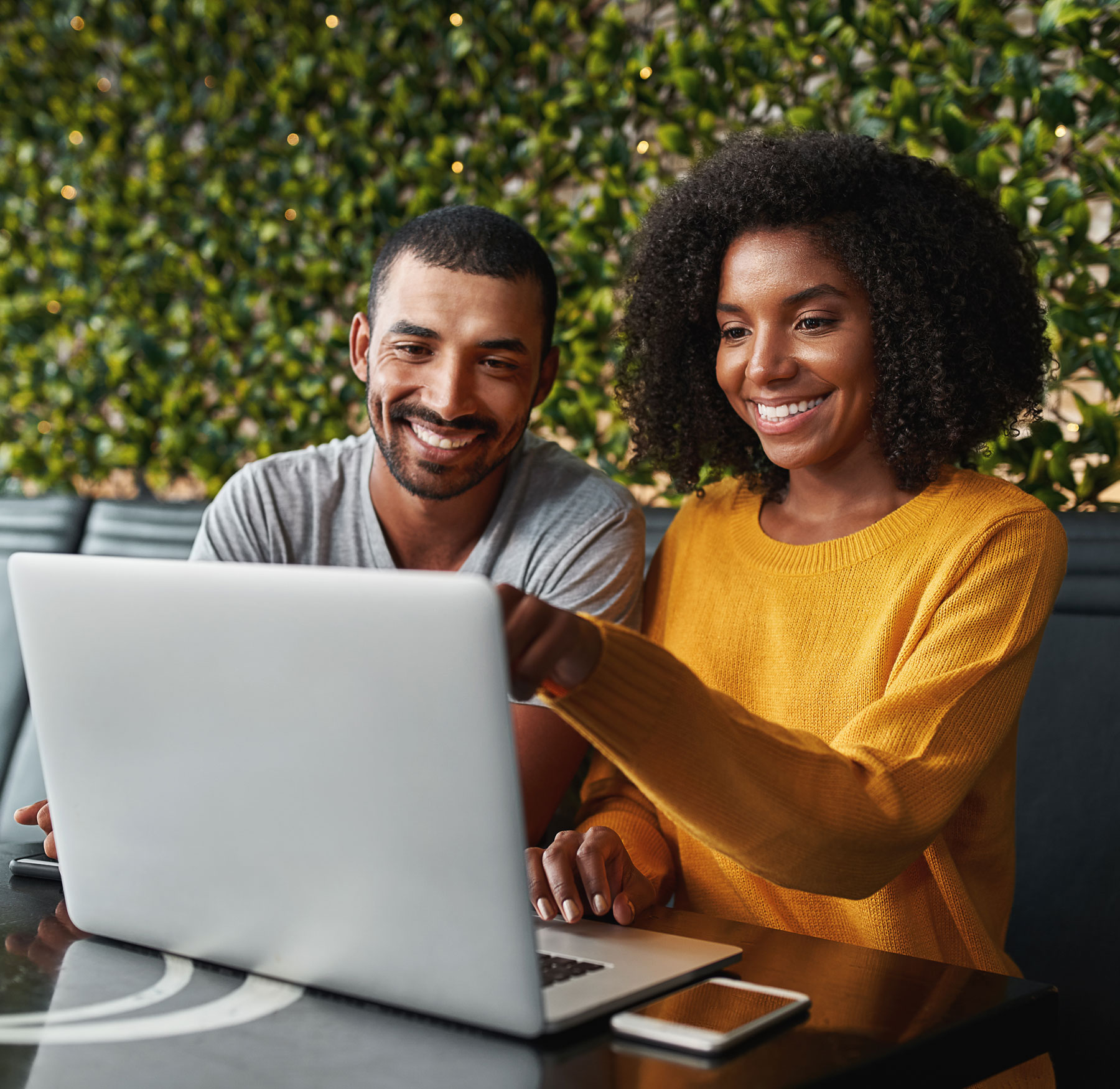 African American couple at cafe looking a laptop smiling