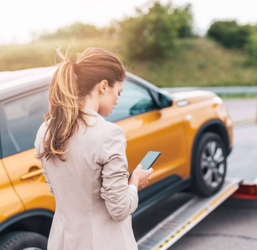 a woman using her mobile device while her automobile is being towed