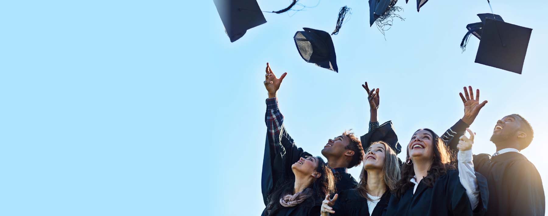 high school graduates throwing caps into blue sky