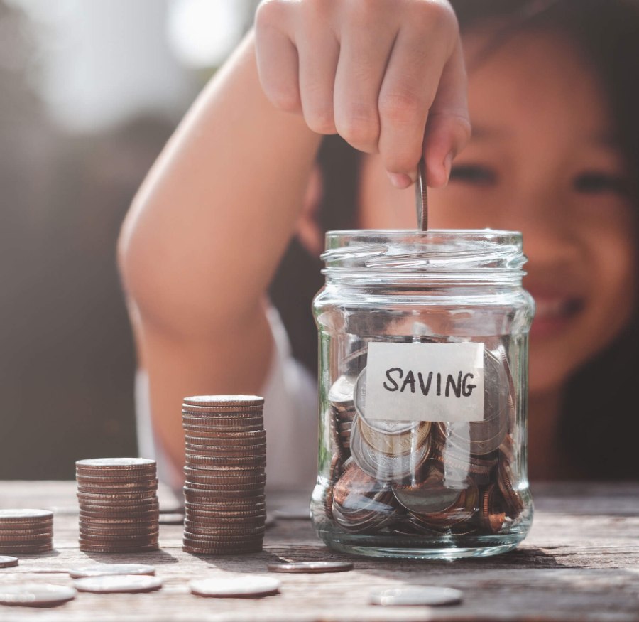 a child putting coins in a savings jar