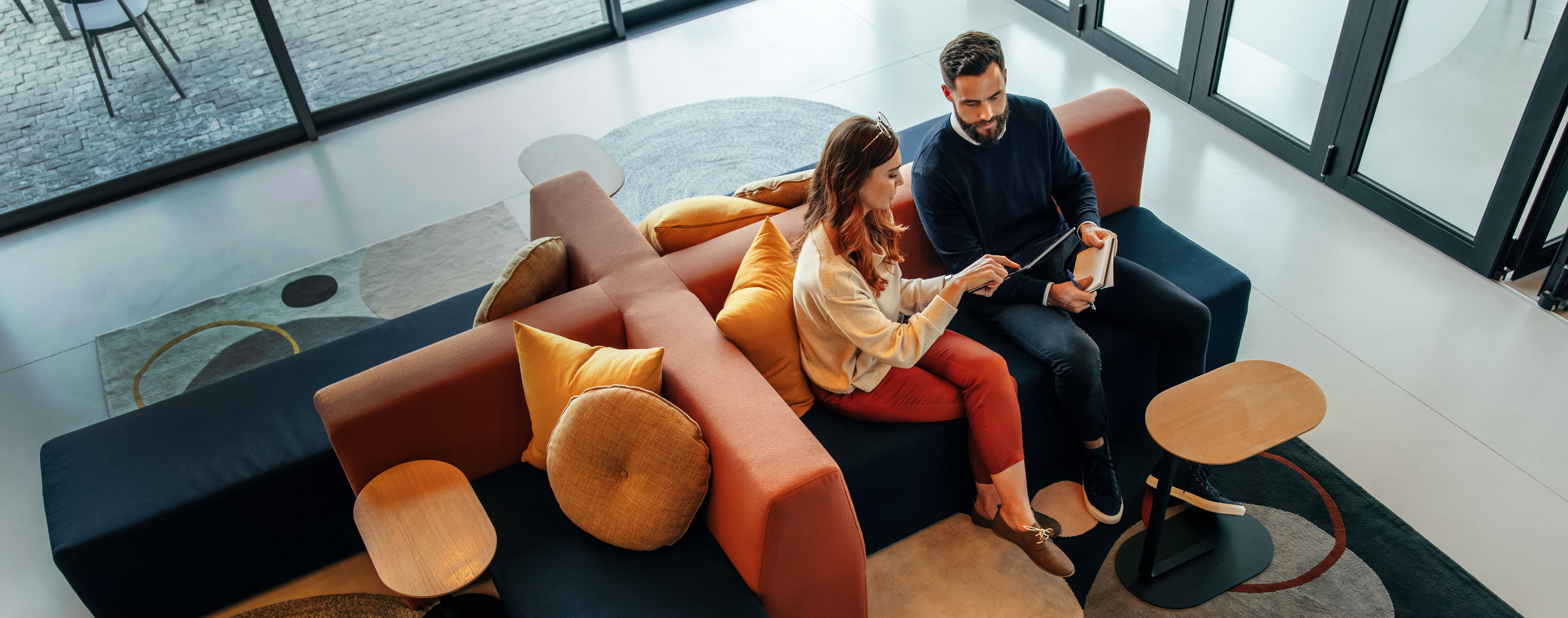 High angle view of two businesspeople working in an office lobby. Two modern businesspeople using a digital tablet while having a discussion. Two young people collaborating on a project.