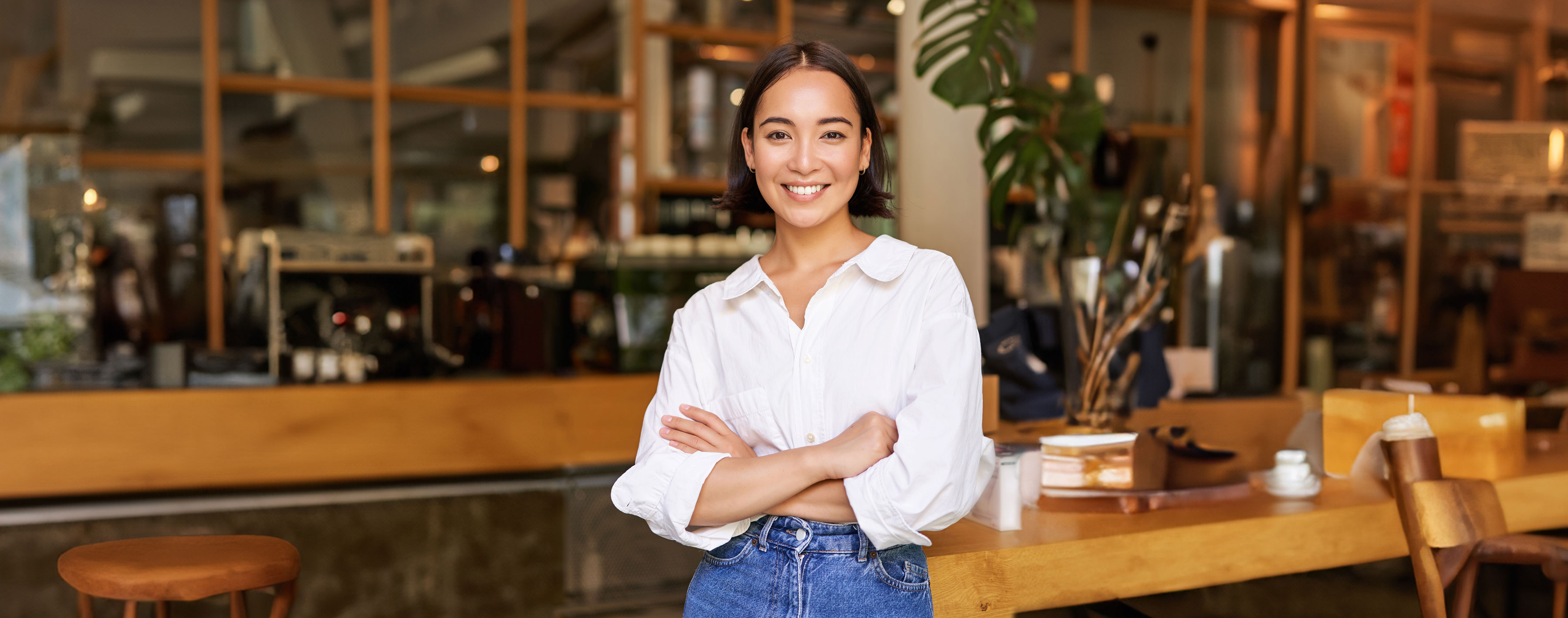 Portrait of young female entrepreneur, cafe owner, standing at the door entrance and smiling, looking confident.