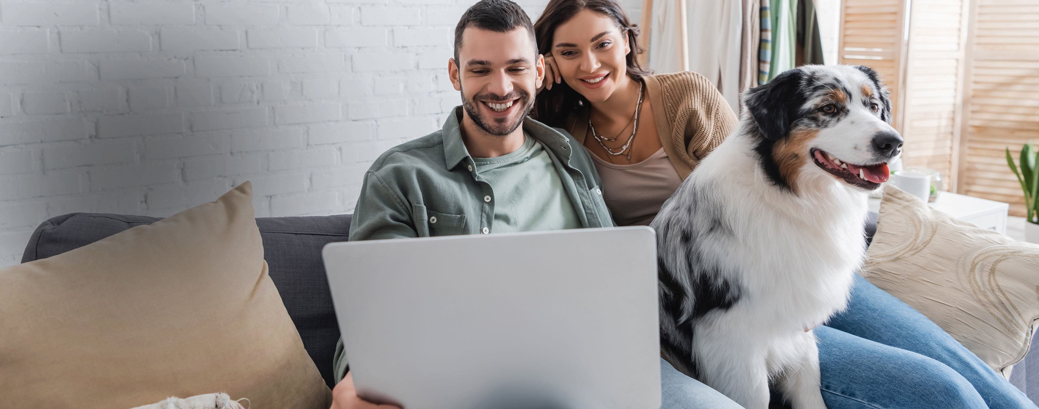 happy young couple watching movie on laptop near Australian shepherd dog