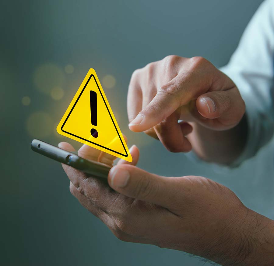 man holding mobile phone with an exclamation point in a yellow triangle graphic above the cell phone