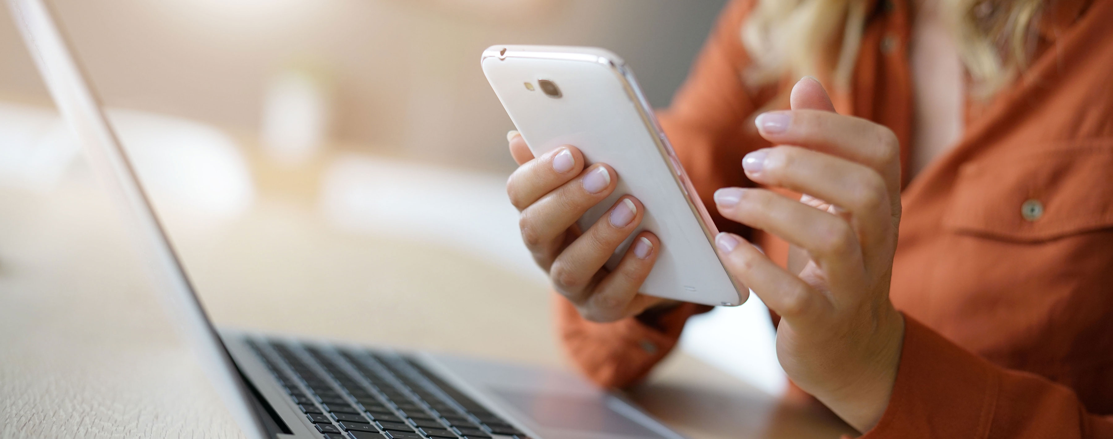 woman looking at mobile phone and laptop computer