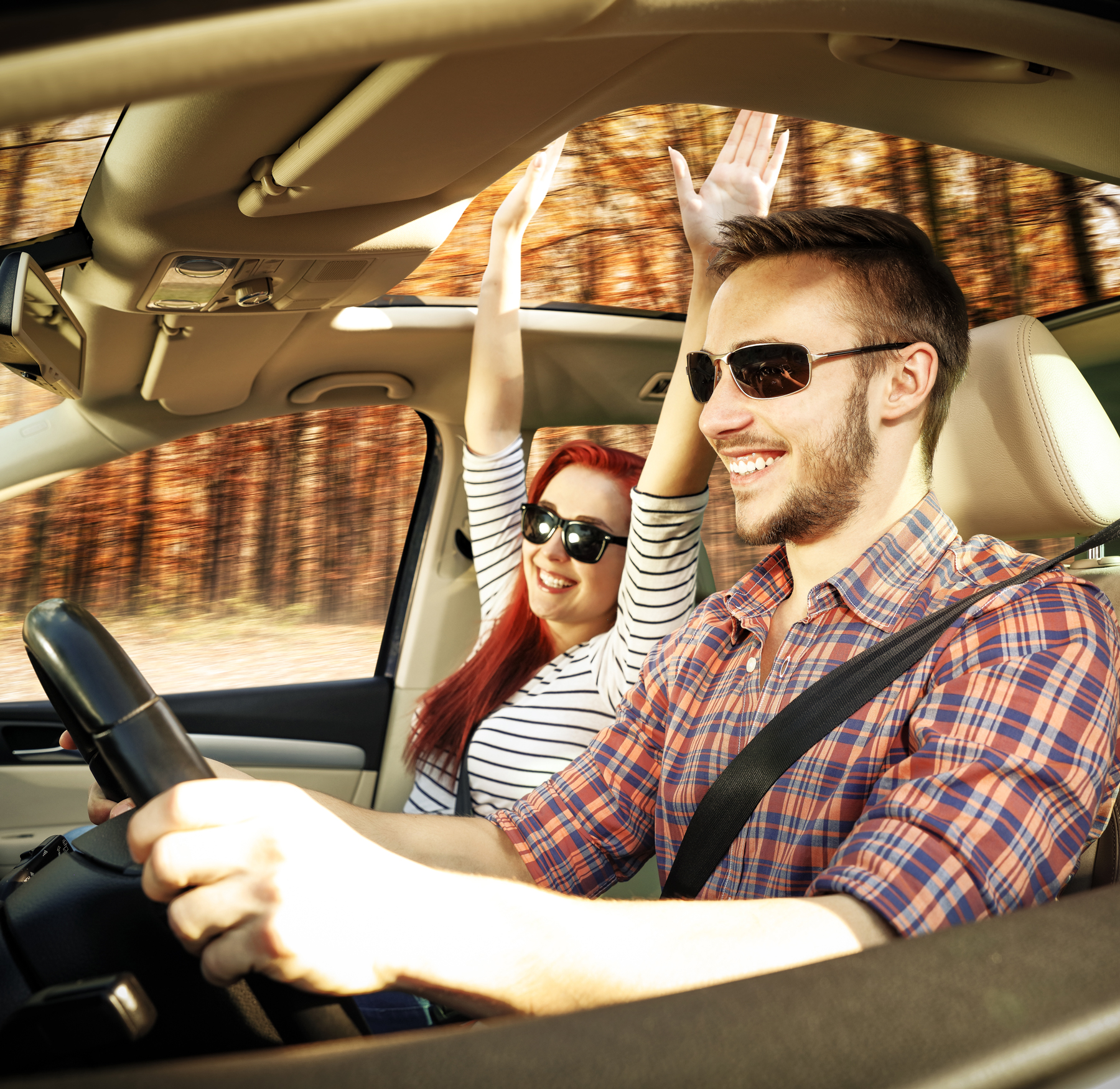 Happy couple riding in car in the fall