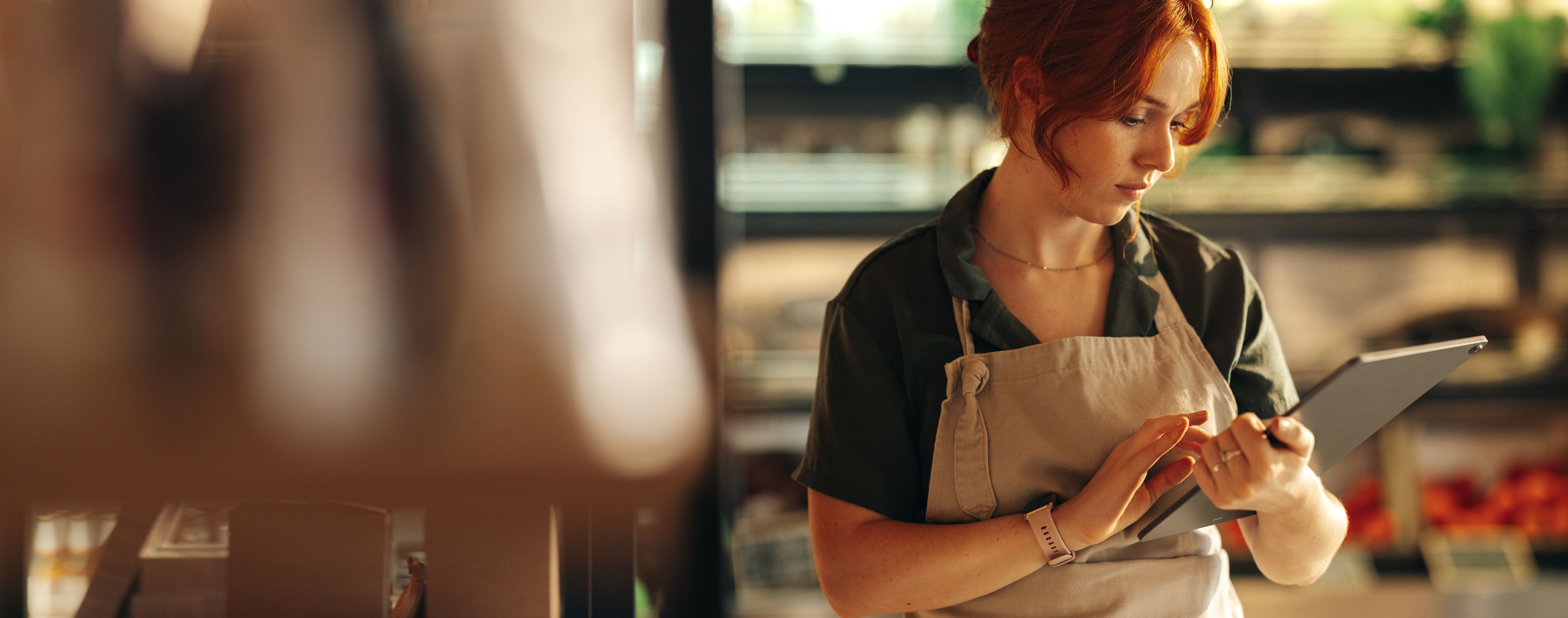 Female shop owner using a digital tablet while standing in her grocery store. Successful entrepreneur running her small business using wireless technology.