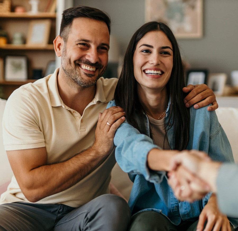 a couple smiling shaking hands with another person